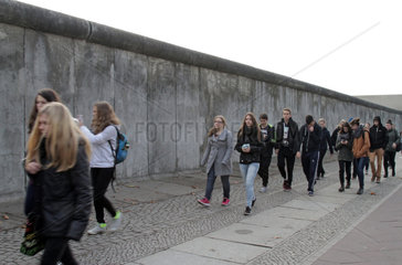 Berlin  Deutschland  Jugendliche laufen an einem Teil der ehemaligen Grenzmauer vorbei