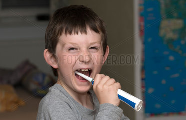 Berlin  Deutschland  Junge putzt sich mit einer elektrischen Zahnbuerste die Zaehne
