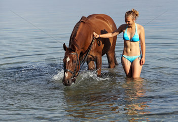 Schwerin  Deutschland  junge Frau steht mit ihrem Pferd im Schweriner See