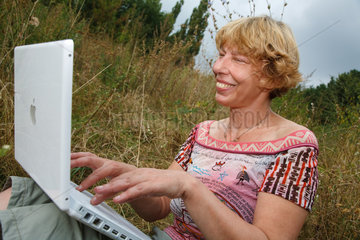 Berlin  Deutschland  eine Frau schreibt Bewerbungen am Laptop auf einer Wiese