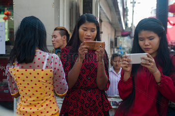 Yangon  Myanmar  Frauen schauen gebannt auf ihre Handys