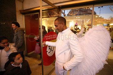 Paris  Frankreich  ein als Engel verkleideter Mann haelt Kunden die Eingangstuer auf