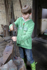 Cammin  Deutschland  Junge bearbeitet eine Eisenstange mit einem Hammer
