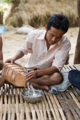 Prahut  Kambodscha  ein junger Mann giesst selbstgebrannten Reiswein in eine Schale