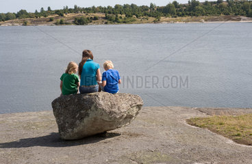 Karlskrona  Schweden  Kinder sitzen auf einem Stein am Ufer und schauen auf die Ostsee