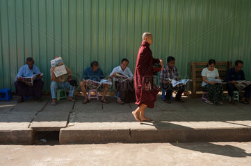 Yangon  Myanmar  Einheimische sitzen am Strassenrand und lesen Zeitung