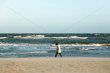 Warnemuende  Deutschland  Frau geht am Strand spazieren
