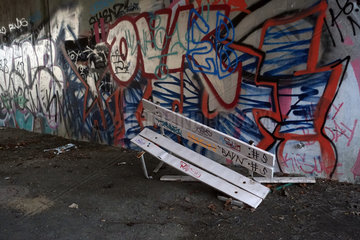 Berlin  Deutschland  Vandalismus  Graffiti an einer Mauer und kaputte Parkbank