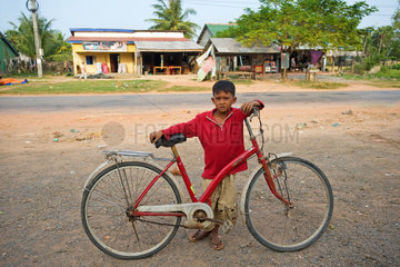 Kampot  Kambodscha  ein Junge mit einem Fahrrad am Strassenrand
