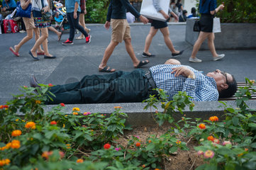 Singapur  Republik Singapur  ein Mann schlaeft auf einer Parbank