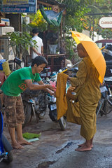 Phnom Penh  Kambodscha  ein Mann gibt einem buddhistischen Moench Opfergaben
