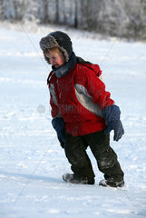 Ingatorp  Schweden  Junge in Winterkleidung laeuft erschoepft einen Abhang hinauf