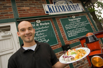 Sellin  Deutschland  Mitarbeiter des Restaurants Selliner Kleinbahnhof mit einem Teller frischem Matjes