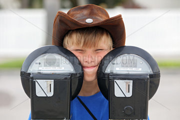 Saint Petersburg  USA  Junge mit Cowboyhut schaut hinter zwei Parkuhren hervor