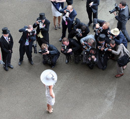 Ascot  Grossbritannien  elegant gekleidete Frau mit Hut posiert vor einer Reihe Fotografen