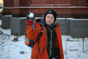 Berlin  Deutschland  Junge zielt drohend mit einem Schneeball auf den Betrachter