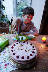 Berlin  Deutschland  Junge schneidet seine Geburtstagstorte an