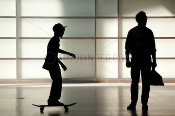 Berlin  Deutschland  Silhouette eines Vaters mit Skateboard fahrendem Sohn