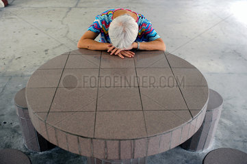 Singapur  Republik Singapur  eine Frau ruht sich an einem Tisch aus
