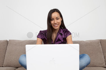 Essen  Deutschland  Frau mit Laptop auf dem Sofa