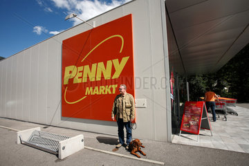 Radenthein  Oesterreich  Mann wartet mit seinem Hund vor einem Penny Markt