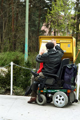 Berlin  Deutschland  ein behinderter Rentner im Rollstuhl am Briefkasten