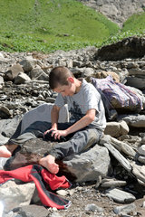 Blatti Alm  Schweiz  ein Junge waescht seine Sachen an einem Fluss