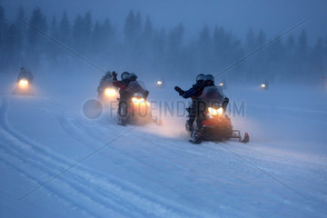 Aekaeskero  Finnland  Maenner fahren bei Nacht auf Schneemobilen