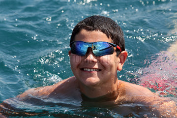 Capodimonte  Italien  Junge mit verspiegelter Sonnenbrille schwimmt in einem See