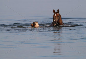 Schwerin  Deutschland  junge Frau schwimmt mit ihrem Pferd im Schweriner See