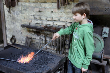 Cammin  Deutschland  Junge erhitzt eine Eisenstange im Feuer