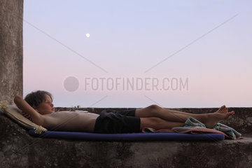 Alicudi  Italien  Junge liegt am Abend auf seiner Matratze und hoert Musik aus seinem i-pod