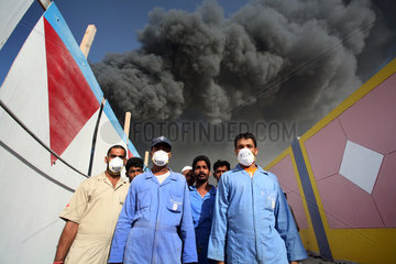 Dubai  Vereinigte Arabische Emirate  Maenner stehen vor einer schwarzen Rauchwolke