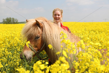 Zachow  Deutschland  junge Frau mit Islandpferd in einem Rapsfeld