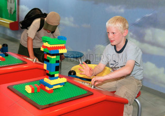 Junge testet Stabilitaet seines Turmes im Legoland