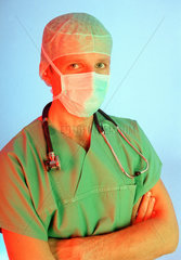 Arzt mit OP-Kleidung  Haube  Mundschutz und einem Stethoskop