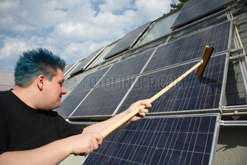 Berlin  Deutschland  Auszubildender putzt ein Solarpanel