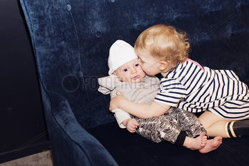 Toddler embracing infant sibling