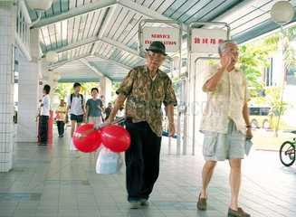 Zwei aeltere Maenner laufen zum Busbahnhof Tampines in Singapur