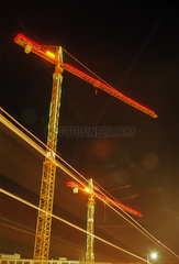 Beleuchtete Baukraene bei Nacht mit Leuchtstreifen von Verkehrslichtern