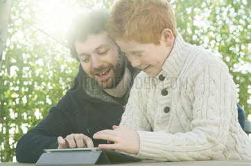 Father and son looking at digital tablet together