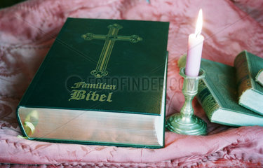 Neben einer Bibel brennt eine Kerze.