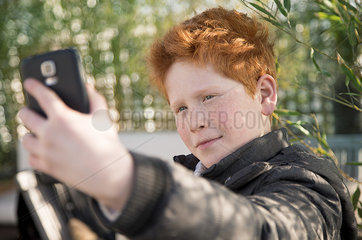 Boy using smartphone to take a selfie