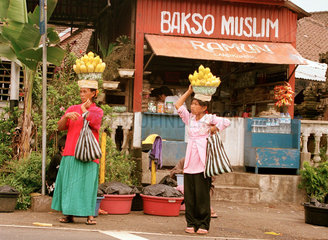 Frauen mit Schalen voller gekochter Maiskolben auf dem Kopf