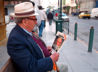 Athen  Ein aelterer Mann liest auf einer Bank