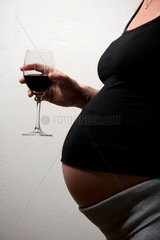 Berlin  Deutschland  eine schwangere Frau haelt ein Rotweinglas in der Hand