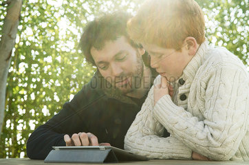 Father and son looking at digital tablet together