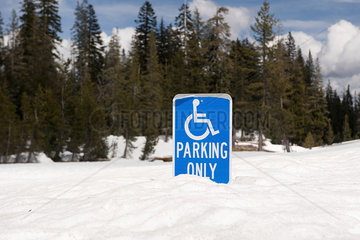 Handicapped parking sign half-buried in deep snow