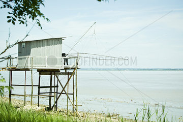 Fishing hut on stilts near water's edge