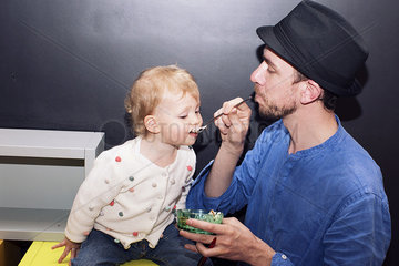 Father spoon feeding toddler